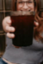 Woman holding a glass of iced coffee toward camera
