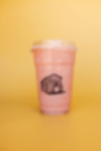 Pink strawberry smoothie in a clear cup with shed logo