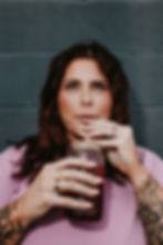 Woman with arm tattoos drinking from a glass jar with straw