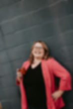 Smiling woman in a pink blazer holding a cup