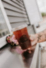 Person with tattoos holding an iced coffee at a window