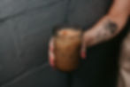Person with arm tattoo holding a glass of iced coffee