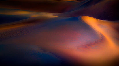 Abstract landscape formed by wind-shaped sand dunes with muted colors and shadows and striking textures, minimalist fine art photography by Marek Boguszak