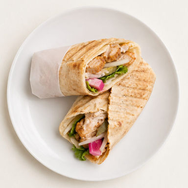 Best chicken shawarma wrap in Windsor Ontario — overhead grilled chicken shawarma wrap halves on a white plate at Aromas Cafe by 7Spices