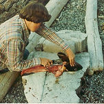 Individual cleaning a fish on the beach