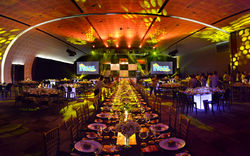 Escena dramática de una cena de gala corporativa con iluminación atmosférica en tonos amarillos y na