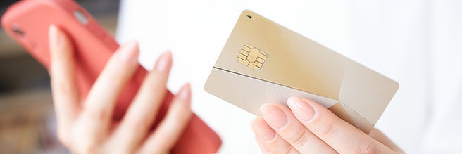 クレジットカードとスマートフォンを持つ女性の手元