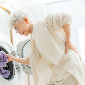 洗濯で腰痛に苦しむシニア女性