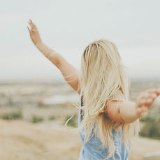 Peaceful lady looking across a landscape with open arms