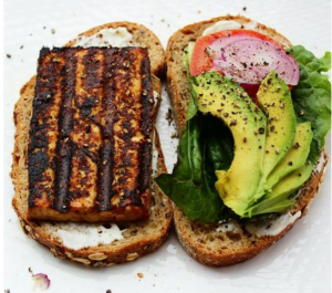 Sanduiche de pão integral, tofu grelhado, homus e avocado