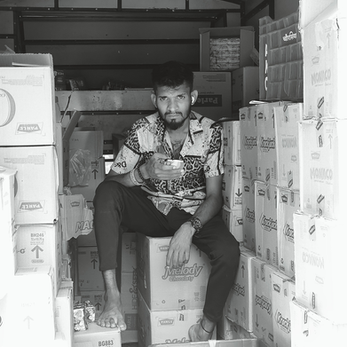 A artsy picture of a delivery worker sitting in tempo and looking into the camera.