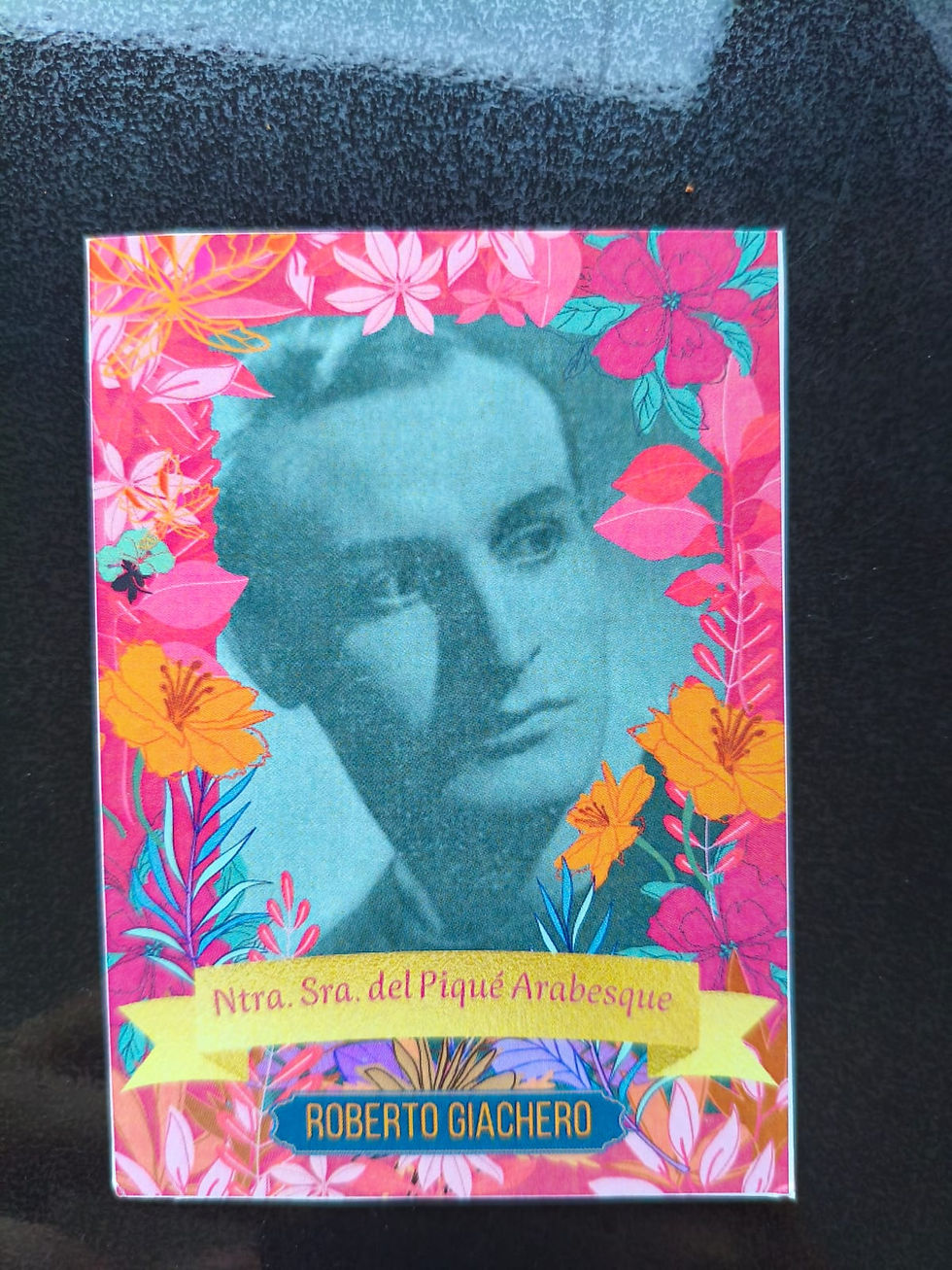 Retrato antiguo enmarcado con flores tropicales; texto Ntra. Sra. del Piqué Arabesque y Roberto Giachero sobre fondo negro.El mar se fue