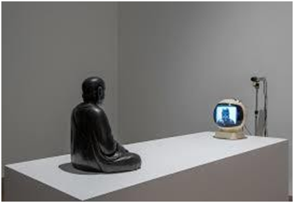 Escultura negra sentada frente a un pequeño monitor en una sala gris minimalista, con luz fría y ambiente silencioso. ¿QUÉ FUTURO PUEDE NACER DE UNA PANTALLA QUE NO SABE DORMIR?