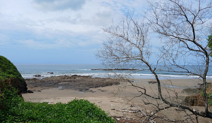 Sandy beach and natural rock formations along Playa Chumico coastline in Pedasí district.