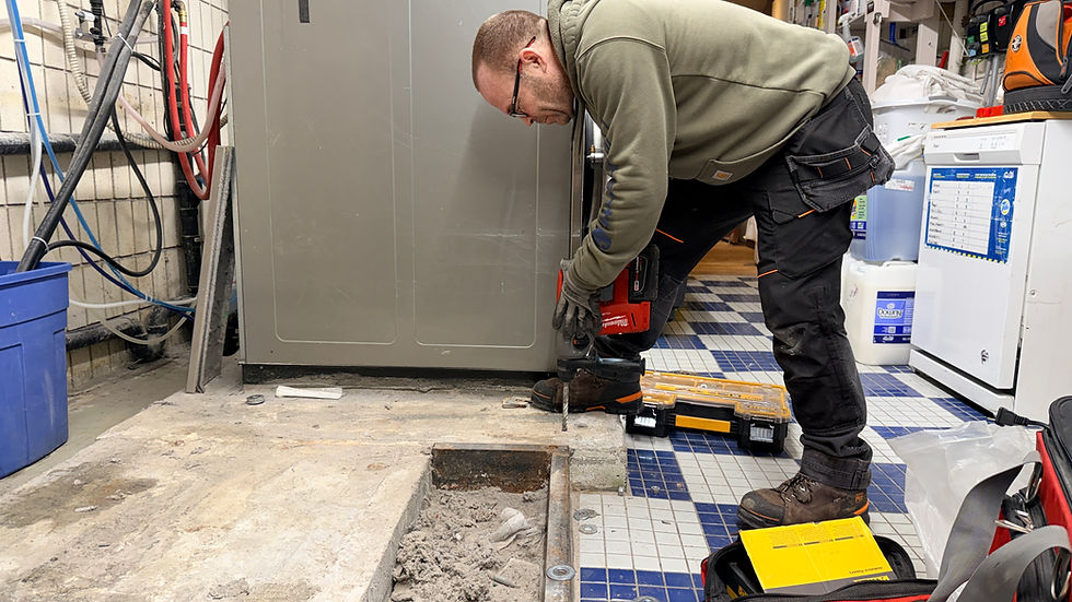 commercial laundry equipment technician drills a hole to install an anchor bolt