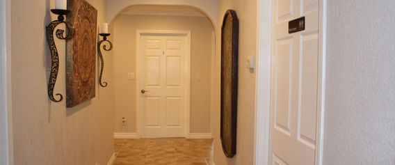 Hallway with tile floor, white doors, sconce, mirror, and "204" sign.