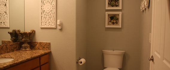 Clean modern bathroom with toilet, granite vanity, and decorative wall art.