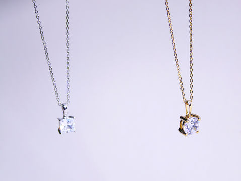Gold and silver necklaces with solitaire diamond pendants displayed on soft background, ideal for jewellery product photography.