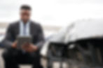 Male insurance adjuster using a digital tablet to document damage from a car accident.