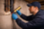 handyman sealing pipes in basement wall