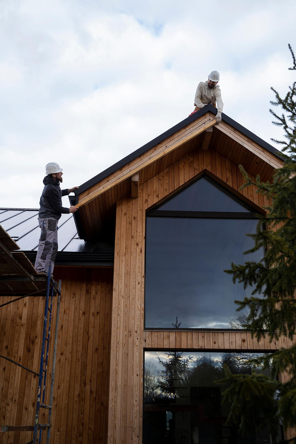 Two people installing eavestrough on a wood trimmed house