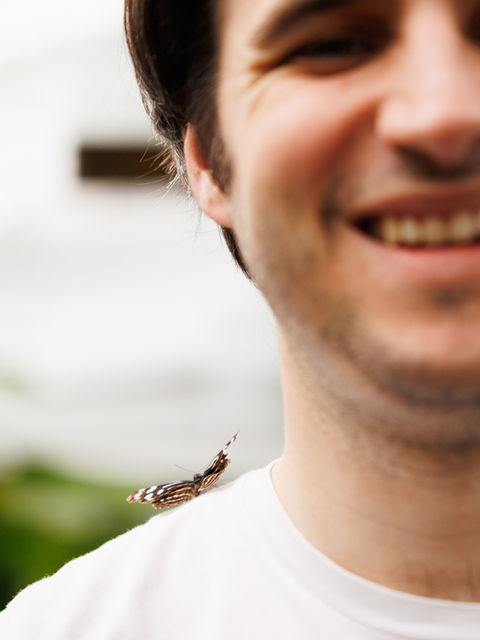 Homme souriant avec un papillon posé sur son épaule