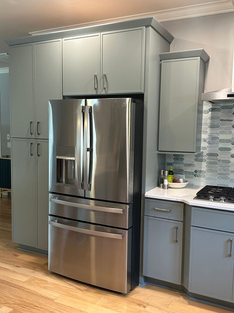 Modern kitchen with stainless steel refrigerator and grey cabinetry design.