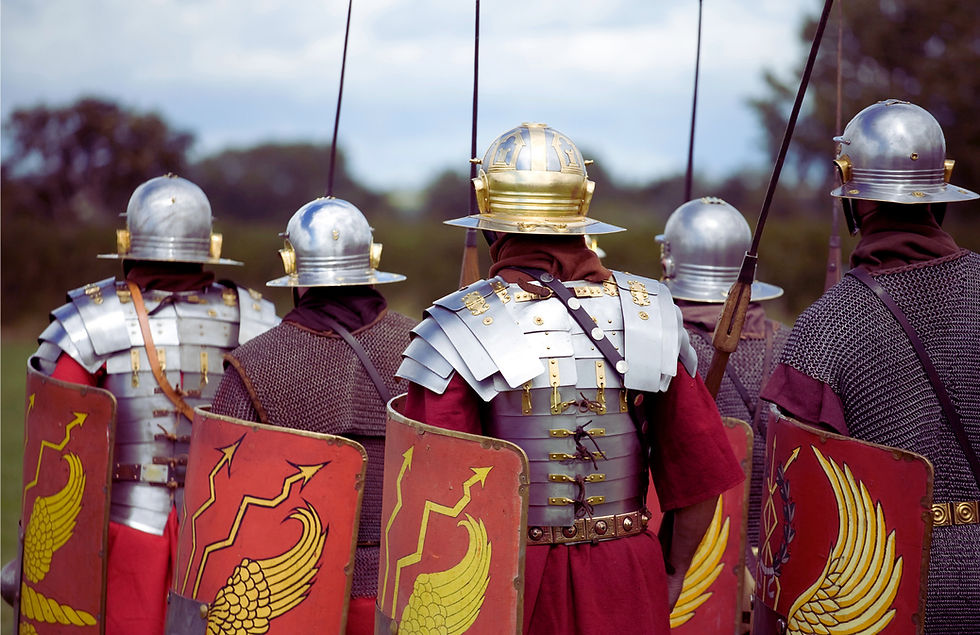 Photo of 5 roman re-enactors marching away from the camera, showcasing the various types of armour worn