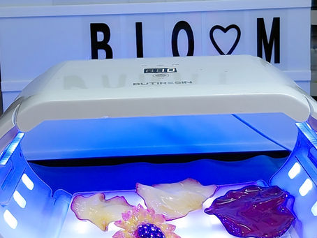 UV lamp curing handmade resin flower jewelry with Danay Bloom sign in the background