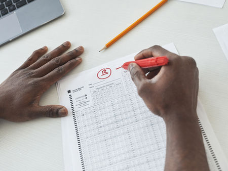 Teacher grading a student assessment to identify learning challenges beyond average test scores