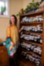 Woman stands beside jars of tinctures and oils during a personalized aromatherapy blend session.