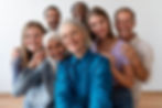 A group of 6 people, diverse in age, gender, and race lean in to pose for a selfie together.