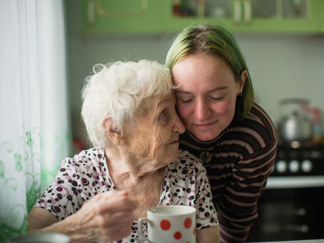 An adult woman rests her forehead affectionately against the foreheard of an elderly woman