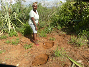 Rosie pointing at a huge footprint of an elephant in Kajire village, rural Kenya