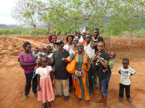 Rosie's family looking very happy in Kajire village, Kenya on the day we installed a rain water harvesting system and water tank at their house. Red soil and trees behind.