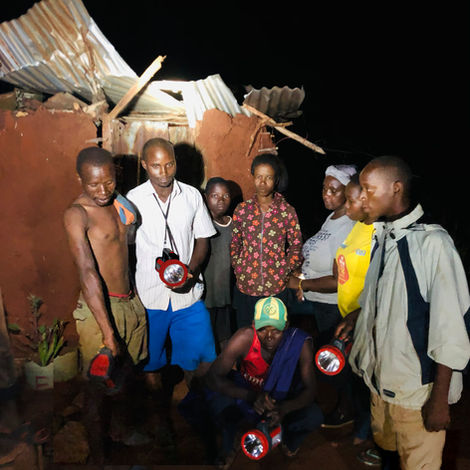 Group in Kajire village, Kenya, using solar torches to warn off an elephant that has wandered off their path and has raided a house for maize