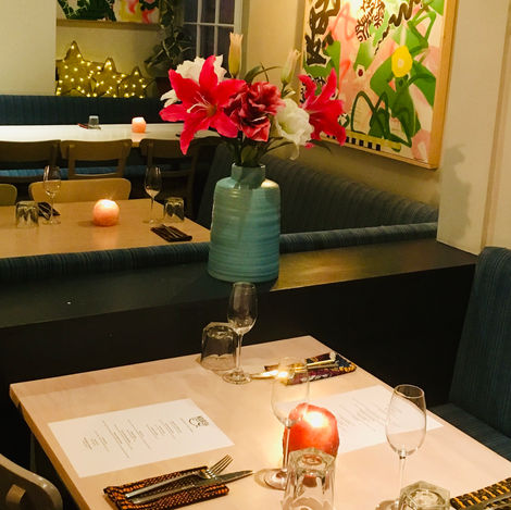 Bright coloured napkins on cream tables in a restaurant with colourful art and flowers in the background