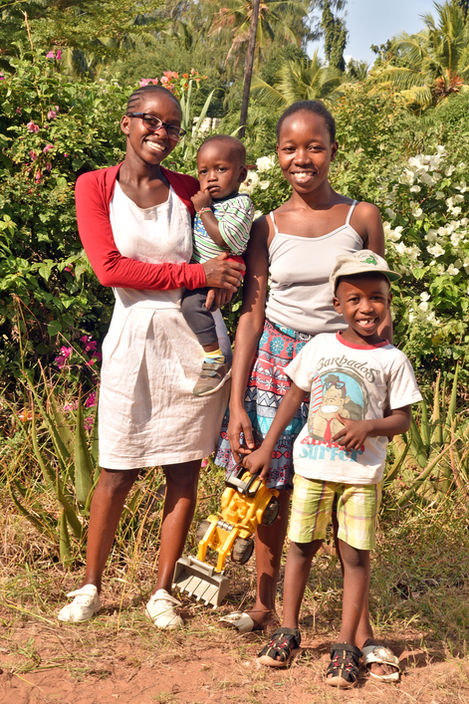 Diffence and BiChao, two of our tailors, standing with their young sons in the sun