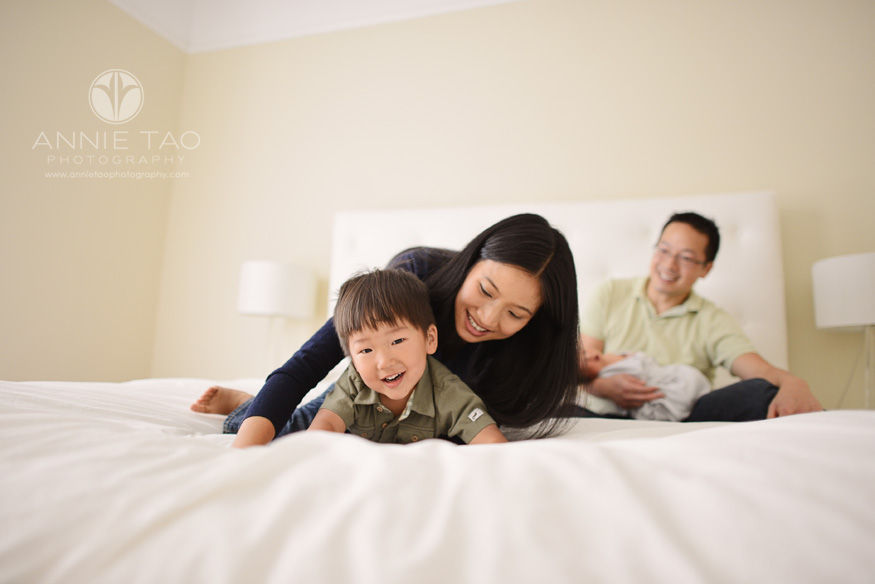 San-Francisco-lifestyle-newborn-family-photography-mother-playing-with-toddler-while-father-holds-baby-in-background