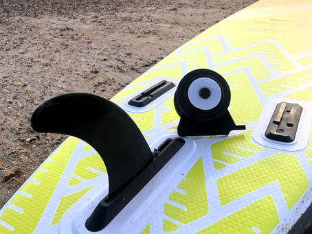 Over turned paddleboard showing the main fin attached and Fin Skate wheels next to it