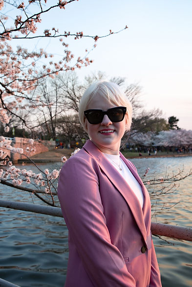 Marissa posing in front of the tidal basin with the cherry blossoms.