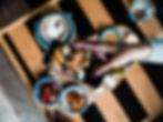 Foreground: Smart phone with a hand taking a photo of food. Background: Food on wooden table