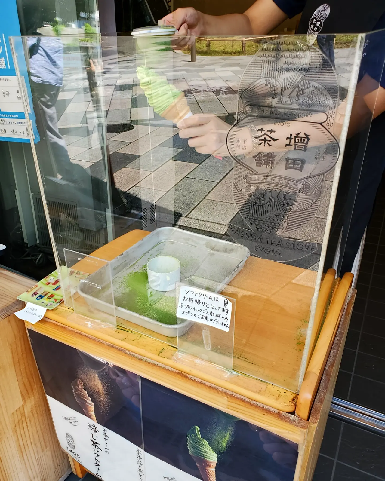 Covering green tea soft-serve ice-cream in matcha powder at Masuda Chaho in Uji, Kyoto Japan.