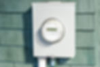 Digital electric smart meter mounted on the exterior wall of a residential home.