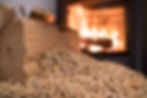 A close-up of eco-friendly wood pellets and firewood with a warm fireplace in the background. A renewable energy source for efficient and sustainable home heating.