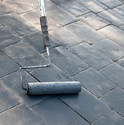 Sealing and painting a gray concrete cobblestone-like driveway with a roller tool