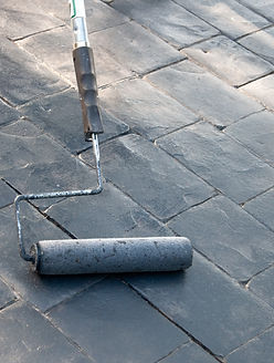 Sealing and painting a gray concrete cobblestone-like driveway with a roller tool..jpg