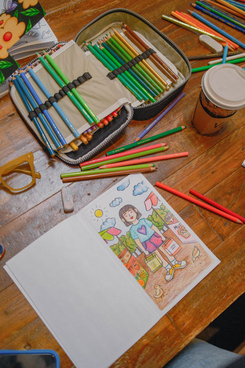 top view of a mini coloring book with coffee and pencils at a coffee shop