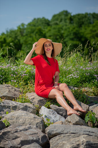 Photoshoot of a young woman at a park sitting on top of rocks with flowers
