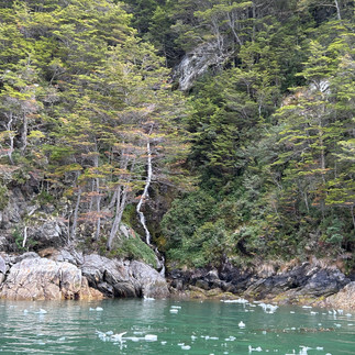 Waterfall over green glacial water